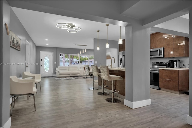 kitchen featuring stainless steel appliances, a kitchen bar, modern cabinets, and light countertops