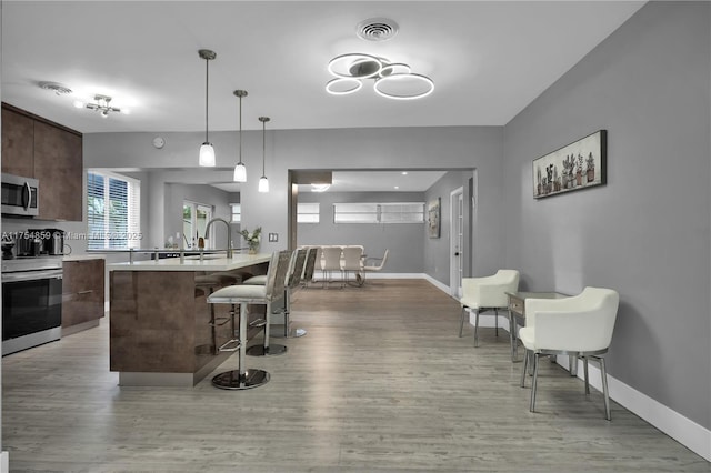 kitchen with visible vents, a breakfast bar, appliances with stainless steel finishes, light countertops, and dark brown cabinets