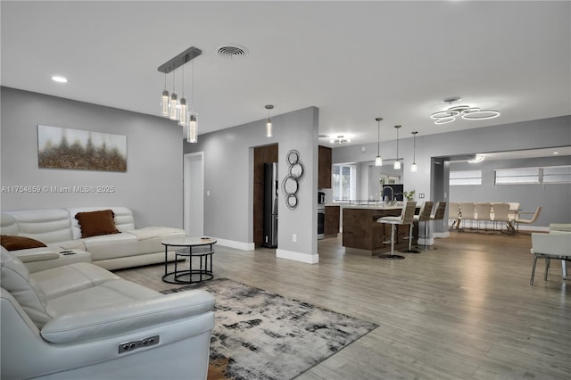 living area featuring visible vents, baseboards, and wood finished floors