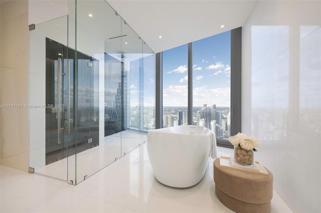 bathroom with a city view, recessed lighting, a freestanding bath, and a wall of windows