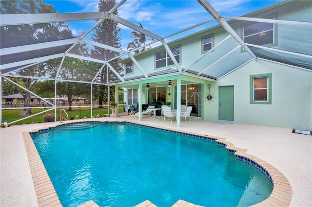 pool featuring glass enclosure, a patio area, and ceiling fan