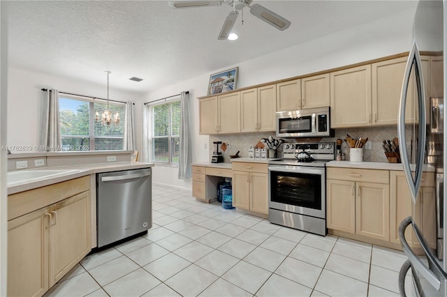 kitchen featuring light brown cabinets, backsplash, stainless steel appliances, light countertops, and light tile patterned floors