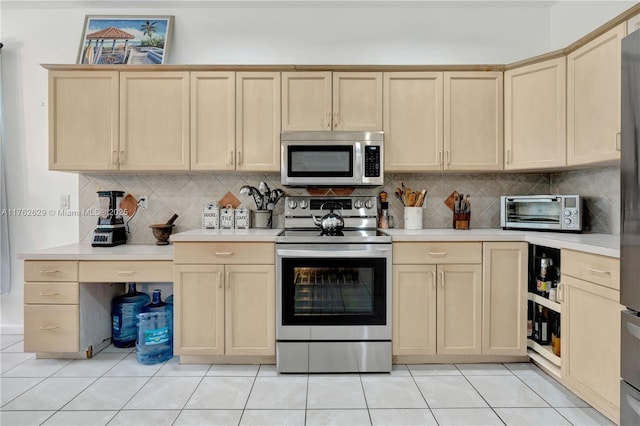 kitchen featuring light countertops, a toaster, appliances with stainless steel finishes, and light brown cabinetry