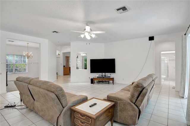 living area with light tile patterned floors, ceiling fan with notable chandelier, visible vents, and a textured ceiling