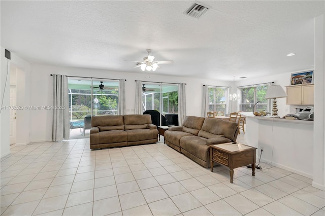 living area featuring light tile patterned floors, visible vents, plenty of natural light, and a textured ceiling