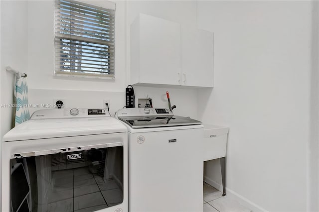 clothes washing area with light tile patterned floors, cabinet space, baseboards, and separate washer and dryer