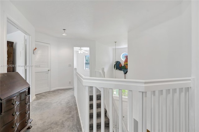 corridor featuring baseboards, an upstairs landing, and carpet flooring