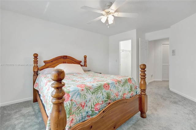 bedroom with a walk in closet, baseboards, carpet, a closet, and a ceiling fan