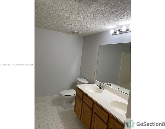 bathroom with tile patterned flooring, a textured ceiling, double vanity, and a sink