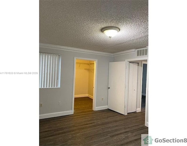 spare room with visible vents, a textured ceiling, dark wood-style floors, and crown molding