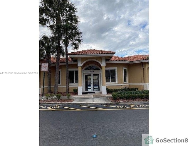 view of front of home with a tile roof, french doors, and stucco siding