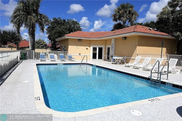 pool with french doors, a patio, and fence