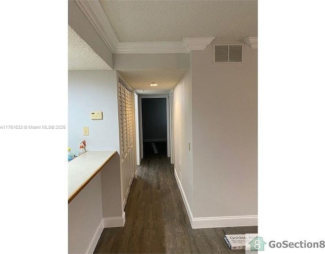 corridor with baseboards, visible vents, dark wood finished floors, a textured ceiling, and crown molding