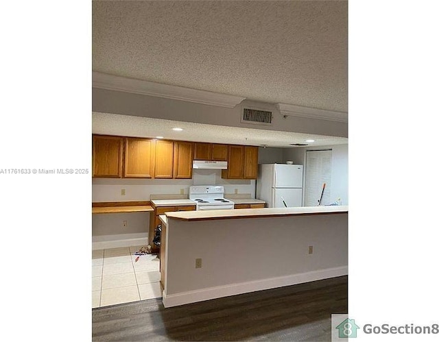 kitchen with white appliances, visible vents, under cabinet range hood, and a textured ceiling