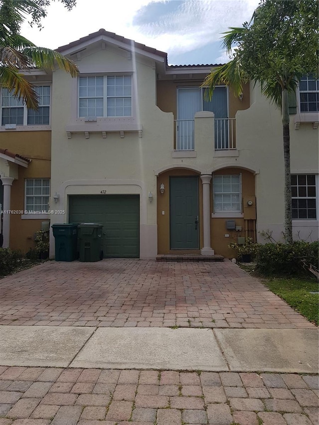 view of front facade featuring stucco siding, an attached garage, and decorative driveway