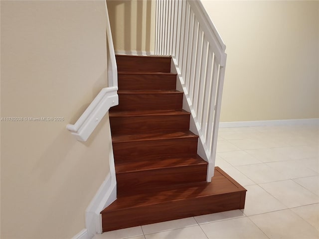 staircase featuring tile patterned floors and baseboards