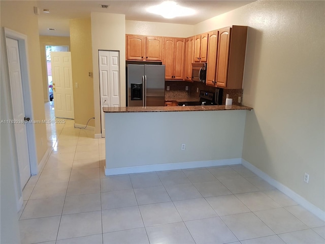 kitchen featuring backsplash, baseboards, dark stone counters, appliances with stainless steel finishes, and a peninsula