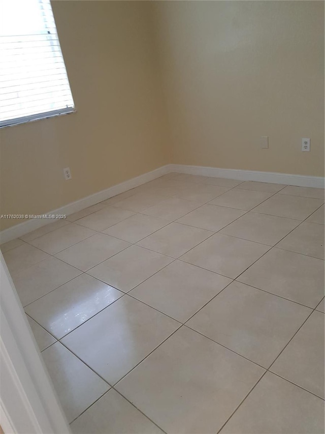 spare room with light tile patterned flooring and baseboards