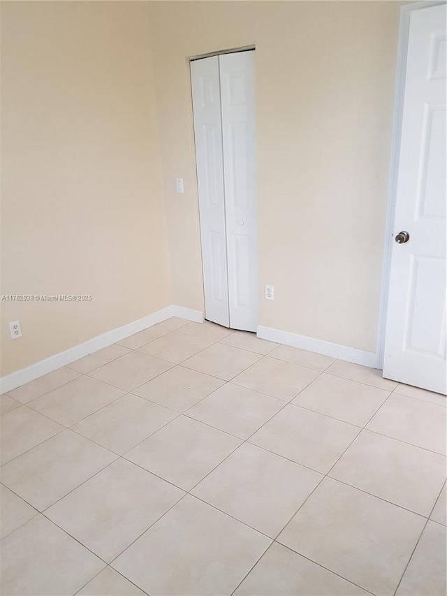 unfurnished bedroom featuring a closet, light tile patterned floors, and baseboards