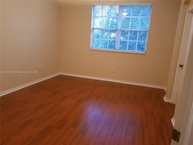 spare room featuring wood finished floors and baseboards