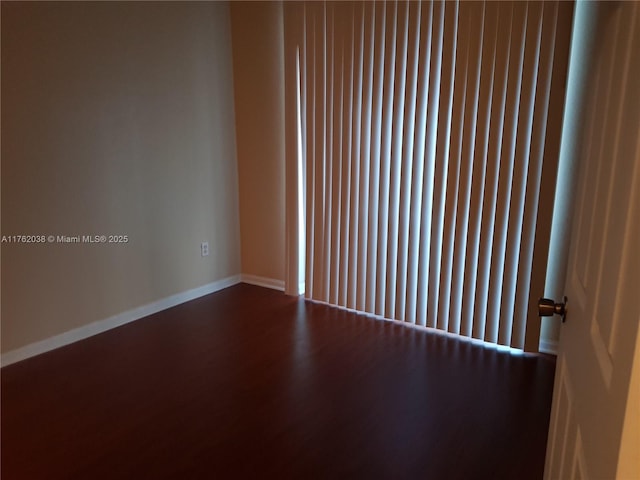 unfurnished room featuring baseboards and dark wood finished floors