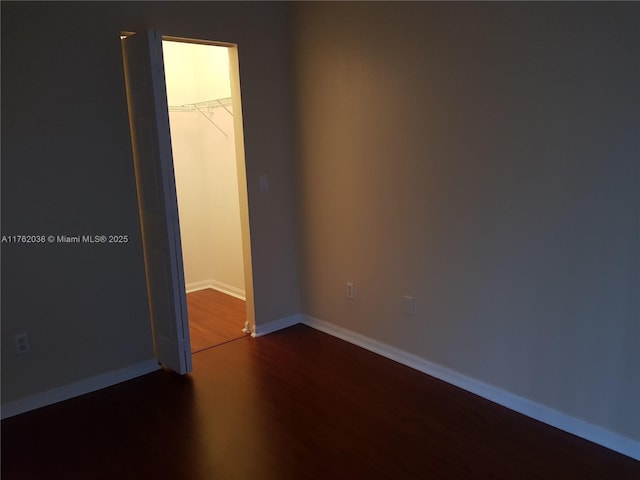 spare room with baseboards and wood finished floors