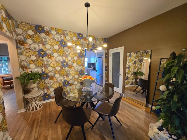 dining area with a chandelier, wallpapered walls, baseboards, and wood finished floors