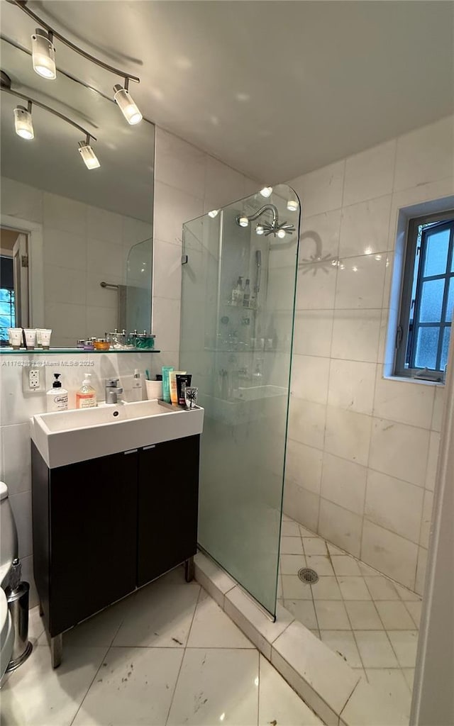 bathroom featuring toilet, tile walls, vanity, and a walk in shower