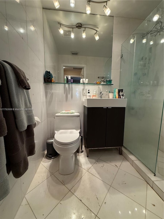 full bathroom featuring vanity, tile walls, toilet, and a shower stall