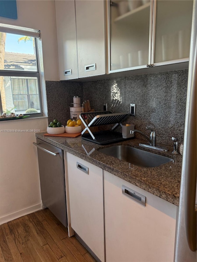 kitchen with decorative backsplash, white cabinets, wood finished floors, and a sink