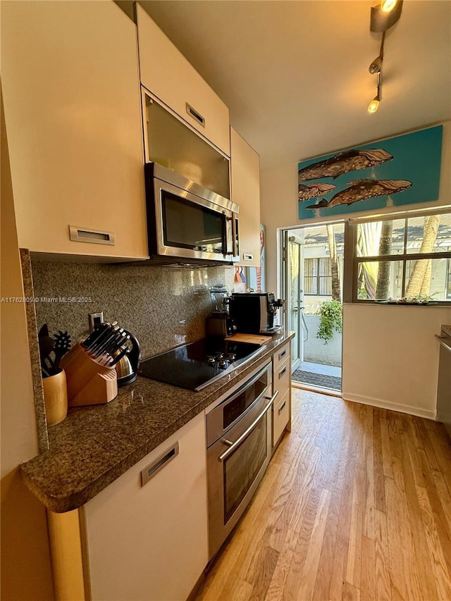 1600 Michigan Ave Unit 1, Miami Beach, FL 33139 - kitchen featuring stainless steel appliances, light wood finished floors, backsplash, white cabinets, and dark stone counters