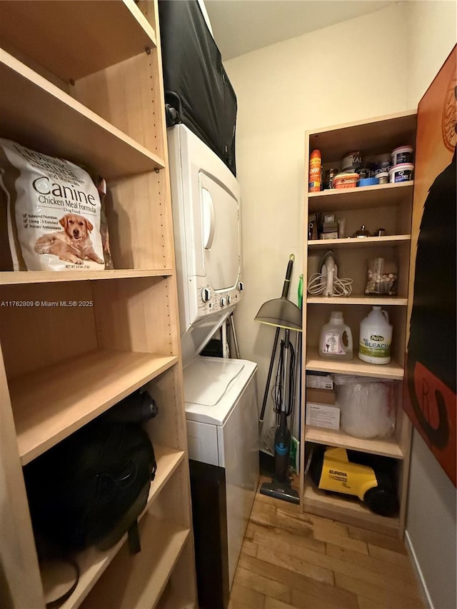 laundry area featuring stacked washer and dryer, wood finished floors, and laundry area