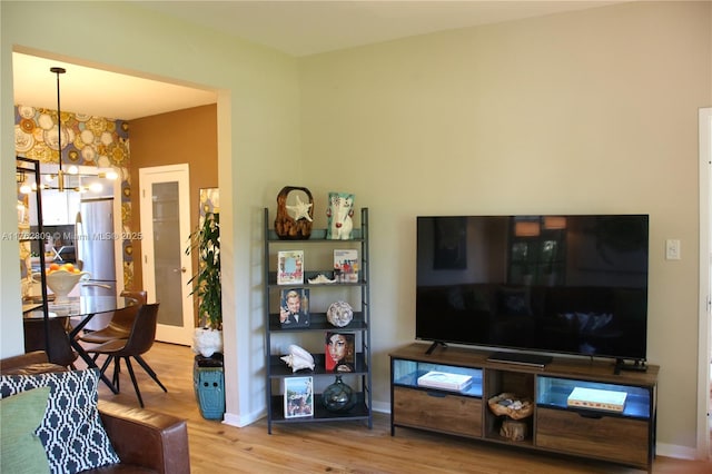 living room featuring baseboards, an inviting chandelier, and wood finished floors