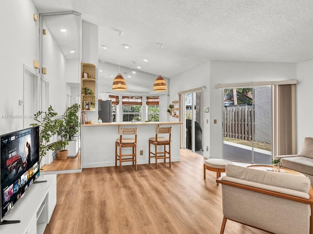 living room featuring lofted ceiling, recessed lighting, light wood-style floors, and a textured ceiling