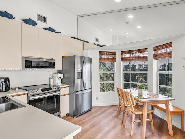 kitchen featuring visible vents, light countertops, lofted ceiling, light wood-style flooring, and appliances with stainless steel finishes