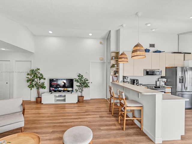 living room with visible vents, a textured ceiling, light wood-style floors, and a towering ceiling