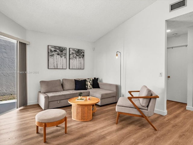 living area featuring visible vents, a textured ceiling, and wood finished floors