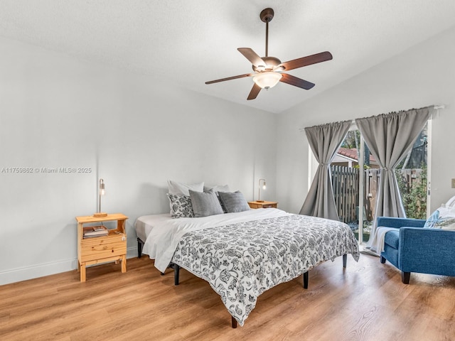 bedroom with access to exterior, light wood finished floors, baseboards, and vaulted ceiling