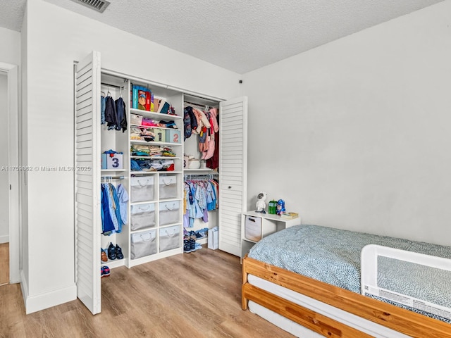 bedroom featuring a closet, a textured ceiling, and wood finished floors