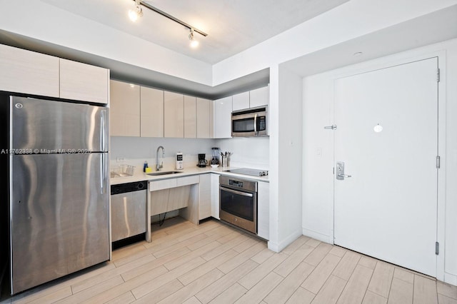 kitchen with a sink, light countertops, light wood-style flooring, stainless steel appliances, and modern cabinets