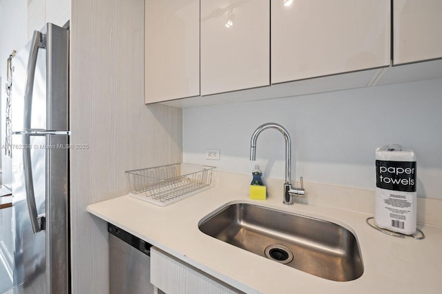 kitchen with white cabinetry, light countertops, appliances with stainless steel finishes, and a sink