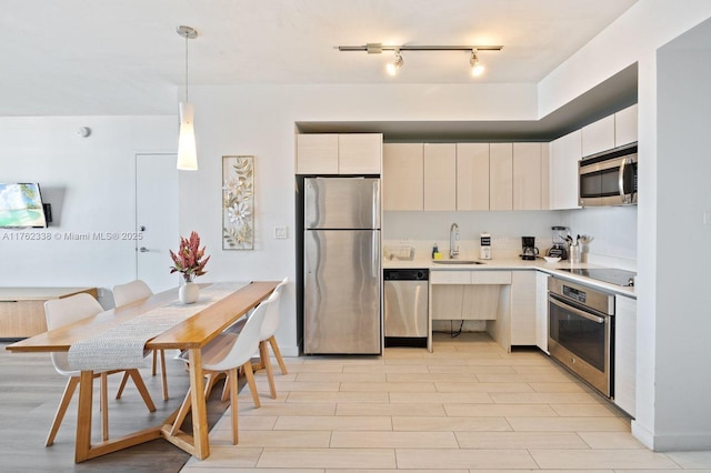 kitchen featuring modern cabinets, light wood-style flooring, a sink, stainless steel appliances, and light countertops