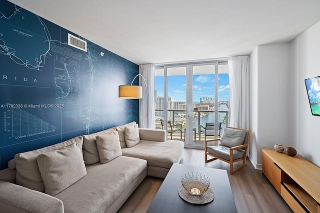 living room with floor to ceiling windows, wood finished floors, and visible vents