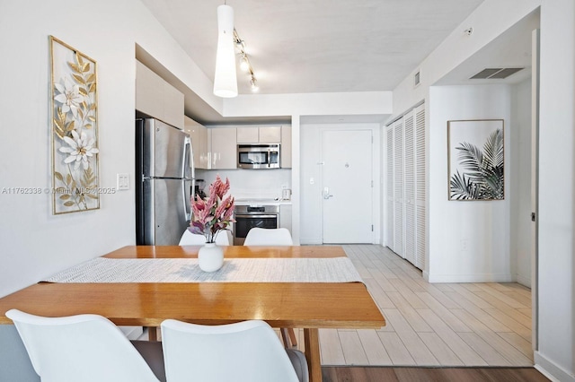 dining space featuring light wood-style flooring, baseboards, and visible vents