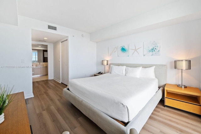 bedroom featuring wood finished floors, visible vents, and a closet