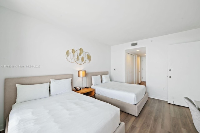 bedroom with wood finished floors, visible vents, and baseboards