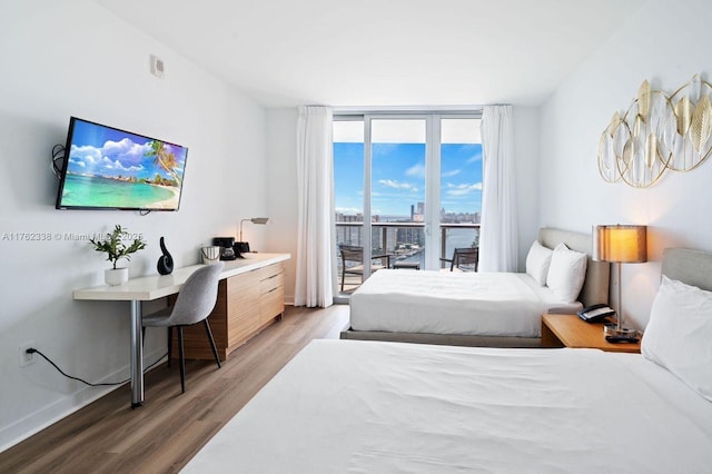 bedroom featuring a wall of windows, baseboards, light wood-style flooring, and access to outside