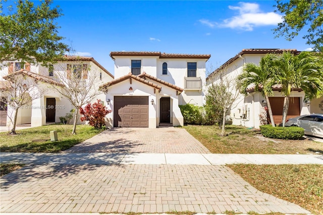 mediterranean / spanish-style home with a tile roof, a front yard, stucco siding, decorative driveway, and an attached garage