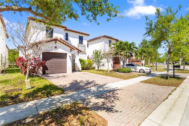 view of front facade with stucco siding, a tiled roof, concrete driveway, and a garage