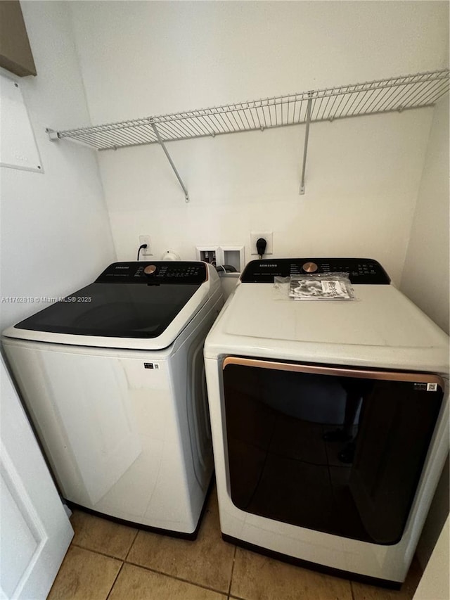 clothes washing area with separate washer and dryer, laundry area, and light tile patterned floors
